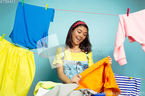 Image of Funny and beautiful housewife doing housework on blue background