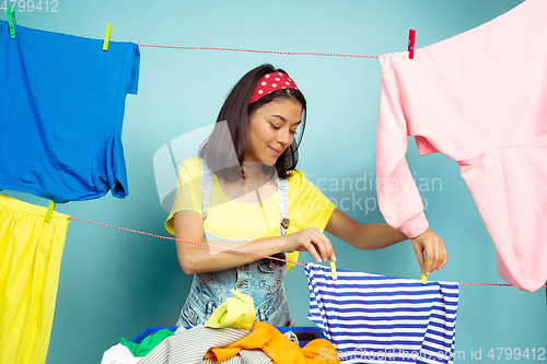 Image of Funny and beautiful housewife doing housework on blue background