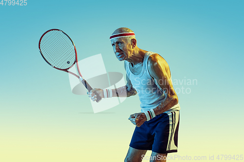 Image of Senior man playing tennis in sportwear on gradient background and neon light