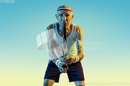 Image of Senior man playing tennis in sportwear on gradient background and neon light