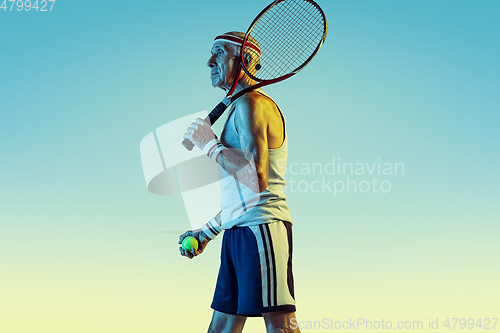 Image of Senior man playing tennis in sportwear on gradient background and neon light