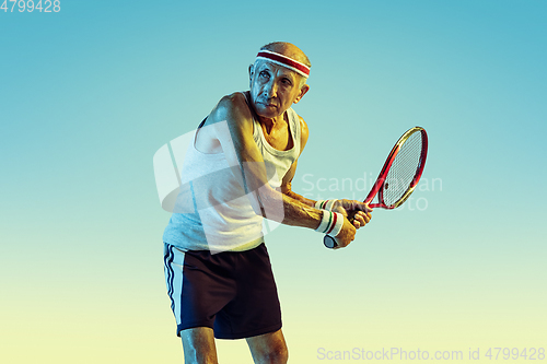 Image of Senior man playing tennis in sportwear on gradient background and neon light