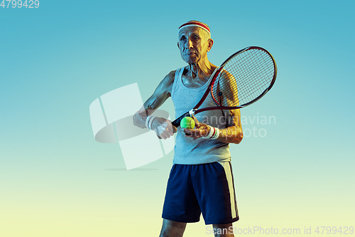 Image of Senior man playing tennis in sportwear on gradient background and neon light