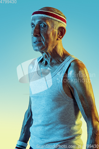 Image of Senior man playing tennis in sportwear on gradient background and neon light