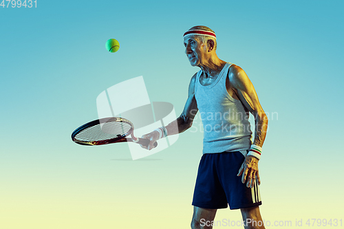 Image of Senior man playing tennis in sportwear on gradient background and neon light