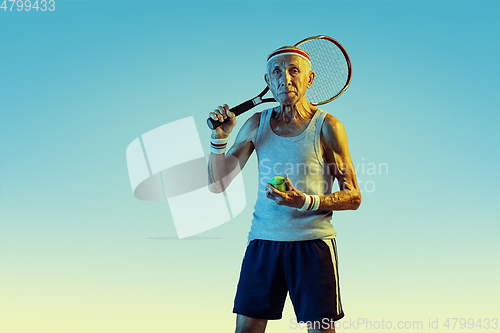 Image of Senior man playing tennis in sportwear on gradient background and neon light