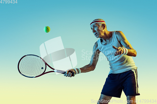 Image of Senior man playing tennis in sportwear on gradient background and neon light