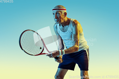 Image of Senior man playing tennis in sportwear on gradient background and neon light