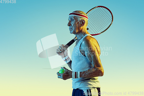 Image of Senior man playing tennis in sportwear on gradient background and neon light