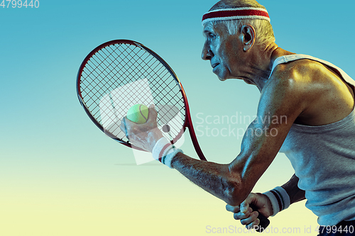 Image of Senior man playing tennis in sportwear on gradient background and neon light