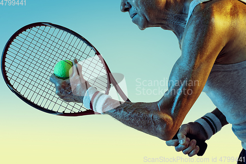 Image of Senior man playing tennis in sportwear on gradient background and neon light