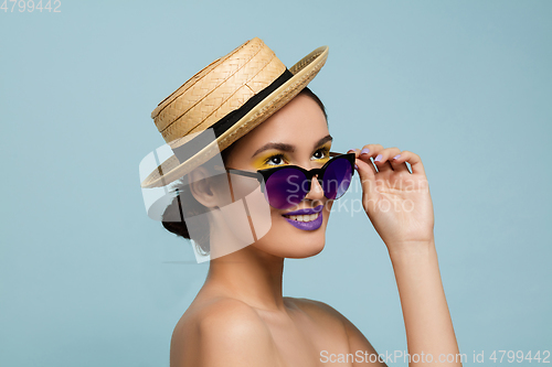 Image of Portrait of beautiful young woman with bright make-up isolated on blue studio background