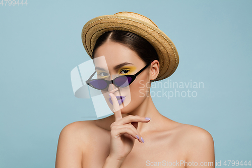 Image of Portrait of beautiful young woman with bright make-up isolated on blue studio background