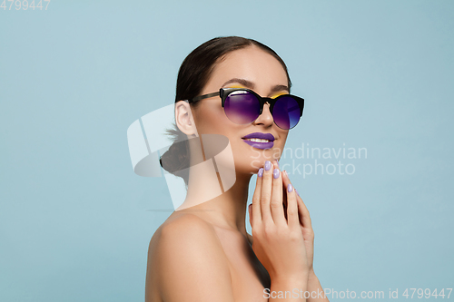 Image of Portrait of beautiful young woman with bright make-up isolated on blue studio background