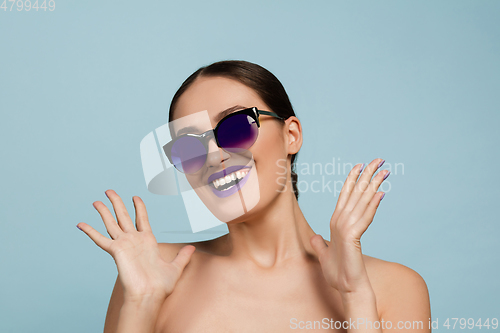 Image of Portrait of beautiful young woman with bright make-up isolated on blue studio background