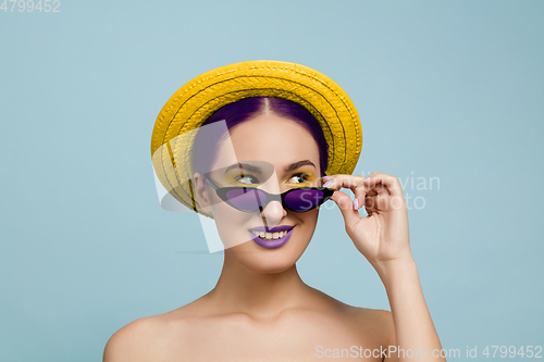 Image of Portrait of beautiful young woman with bright make-up isolated on blue studio background