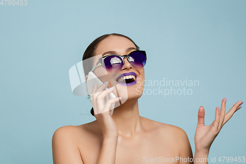 Image of Portrait of beautiful young woman with bright make-up isolated on blue studio background