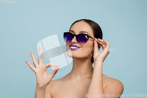 Image of Portrait of beautiful young woman with bright make-up isolated on blue studio background