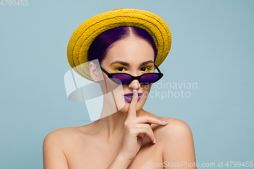 Image of Portrait of beautiful young woman with bright make-up isolated on blue studio background