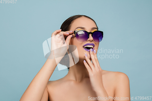 Image of Portrait of beautiful young woman with bright make-up isolated on blue studio background