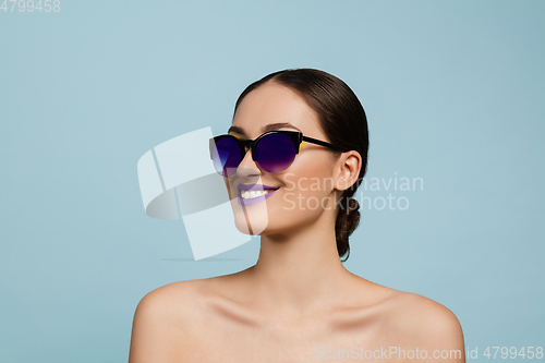 Image of Portrait of beautiful young woman with bright make-up isolated on blue studio background