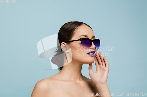 Image of Portrait of beautiful young woman with bright make-up isolated on blue studio background