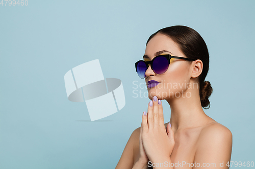 Image of Portrait of beautiful young woman with bright make-up isolated on blue studio background