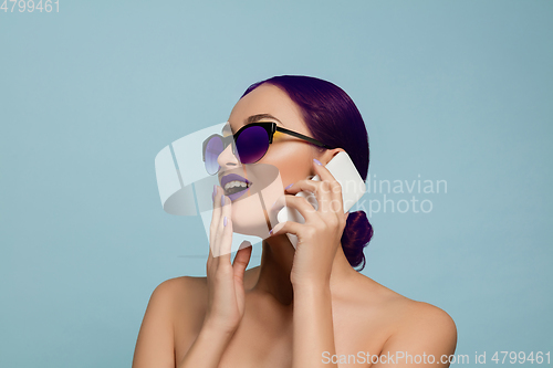 Image of Portrait of beautiful young woman with bright make-up isolated on blue studio background