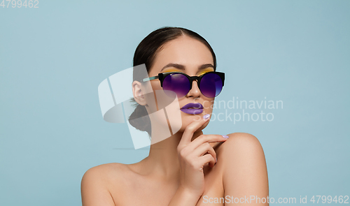 Image of Portrait of beautiful young woman with bright make-up isolated on blue studio background