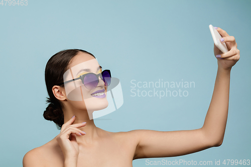 Image of Portrait of beautiful young woman with bright make-up isolated on blue studio background