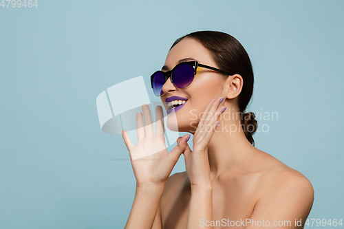 Image of Portrait of beautiful young woman with bright make-up isolated on blue studio background