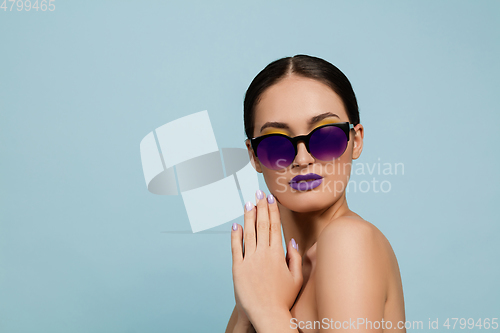 Image of Portrait of beautiful young woman with bright make-up isolated on blue studio background