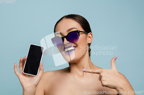 Image of Portrait of beautiful young woman with bright make-up isolated on blue studio background
