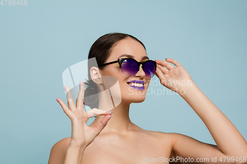 Image of Portrait of beautiful young woman with bright make-up isolated on blue studio background