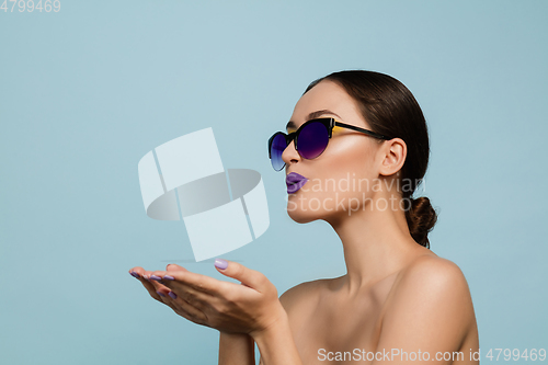 Image of Portrait of beautiful young woman with bright make-up isolated on blue studio background