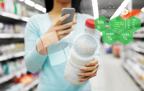 Image of woman with smartphone buying milk at supermarket