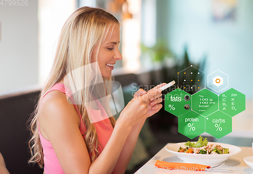 Image of happy woman with smartphone eating at restaurant