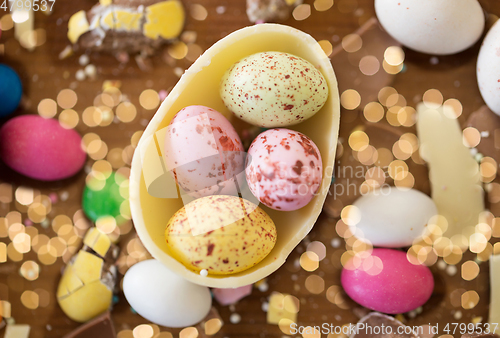 Image of chocolate egg and candy drops on wooden table