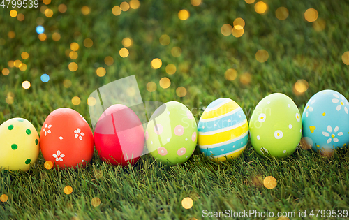 Image of row of colored easter eggs on artificial grass