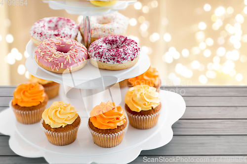 Image of glazed donuts, cupcakes with frosting on stand