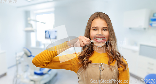 Image of girl with magnifier shows teeth at dental clinic