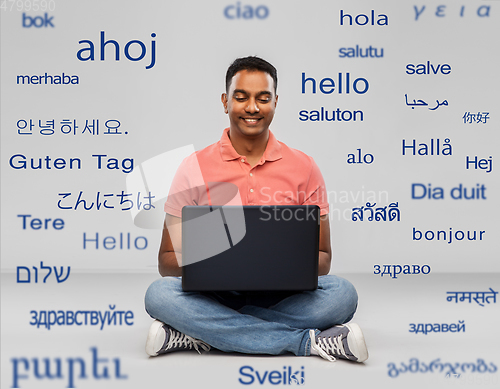 Image of happy indian man with laptop computer on floor