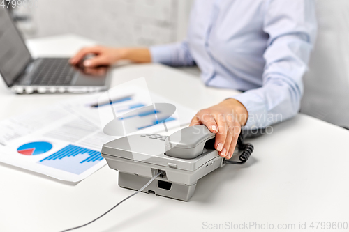 Image of businesswoman calling on desk phone at office