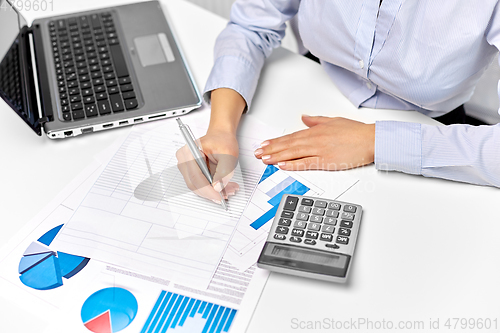 Image of businesswoman with papers, laptop and calculator