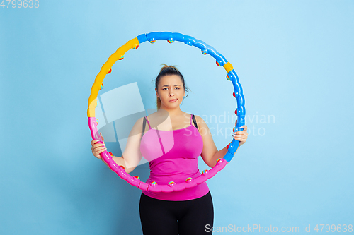 Image of Young caucasian plus size female model\'s training on blue background