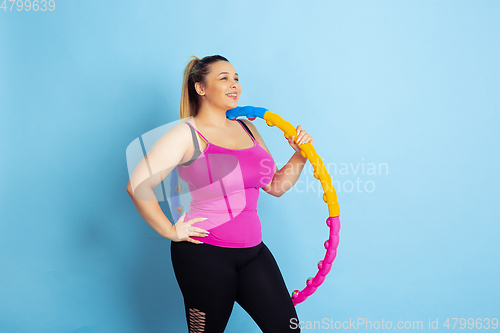 Image of Young caucasian plus size female model\'s training on blue background