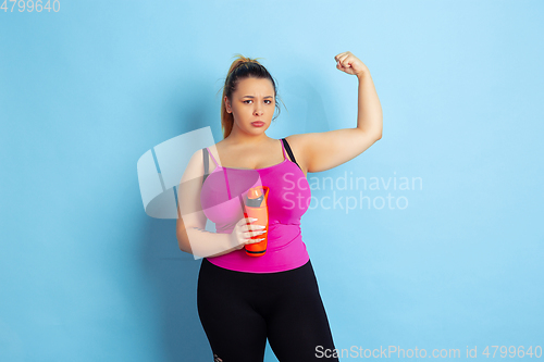 Image of Young caucasian plus size female model\'s training on blue background