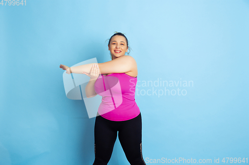 Image of Young caucasian plus size female model\'s training on blue background