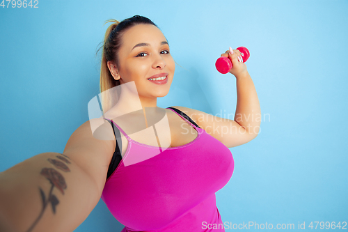 Image of Young caucasian plus size female model\'s training on blue background