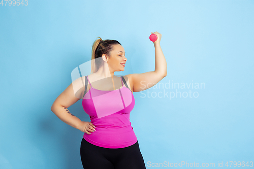 Image of Young caucasian plus size female model\'s training on blue background